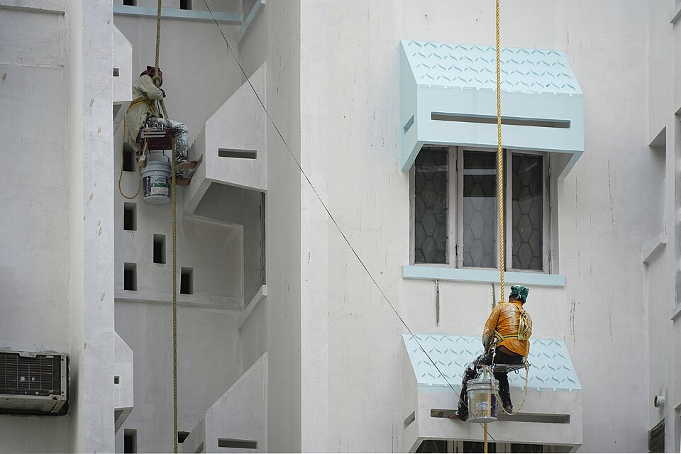 Two painters on ropes painting a building exterior